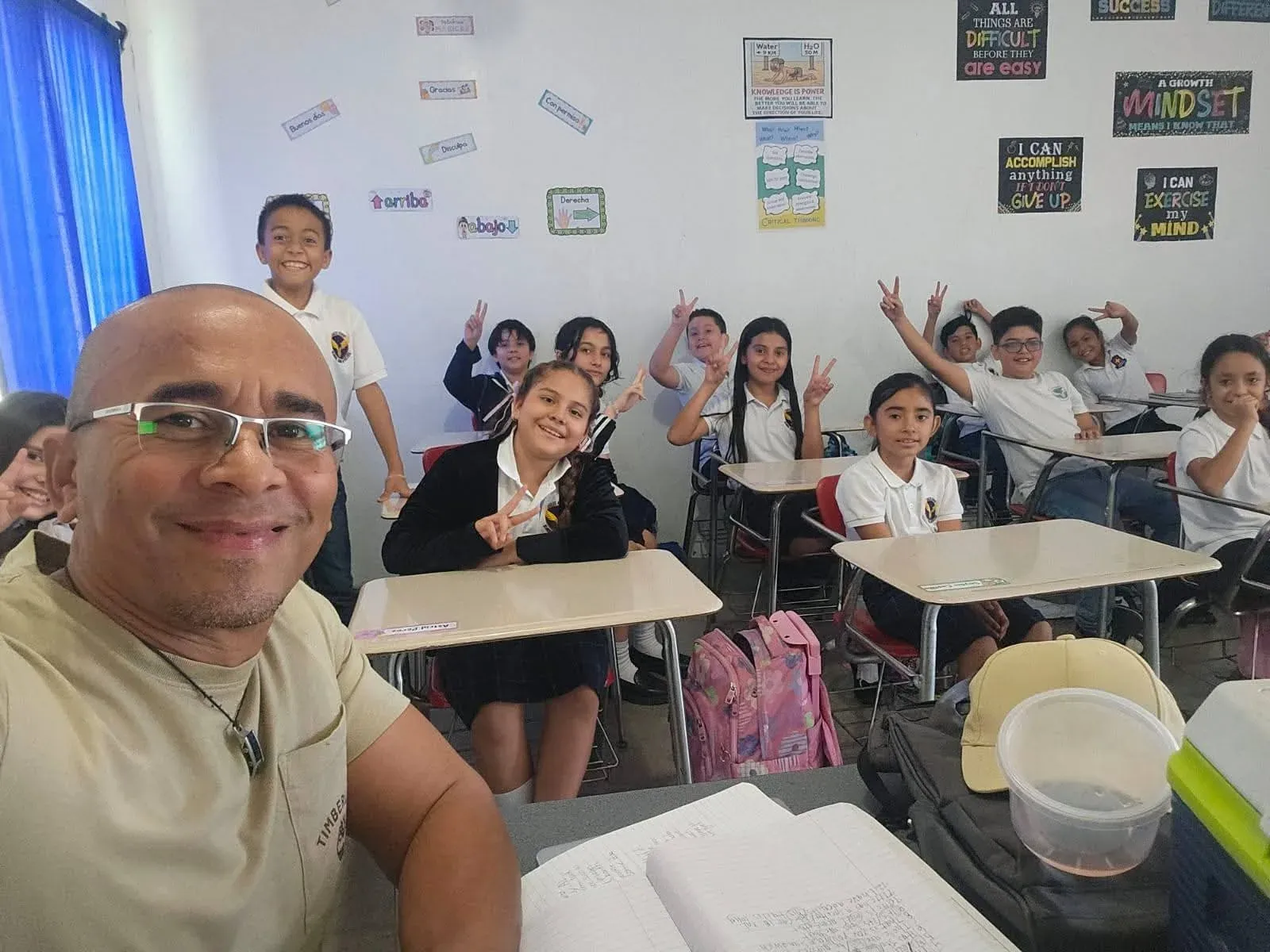 Docente y alumnos de básica sonriendo en su salón de clases