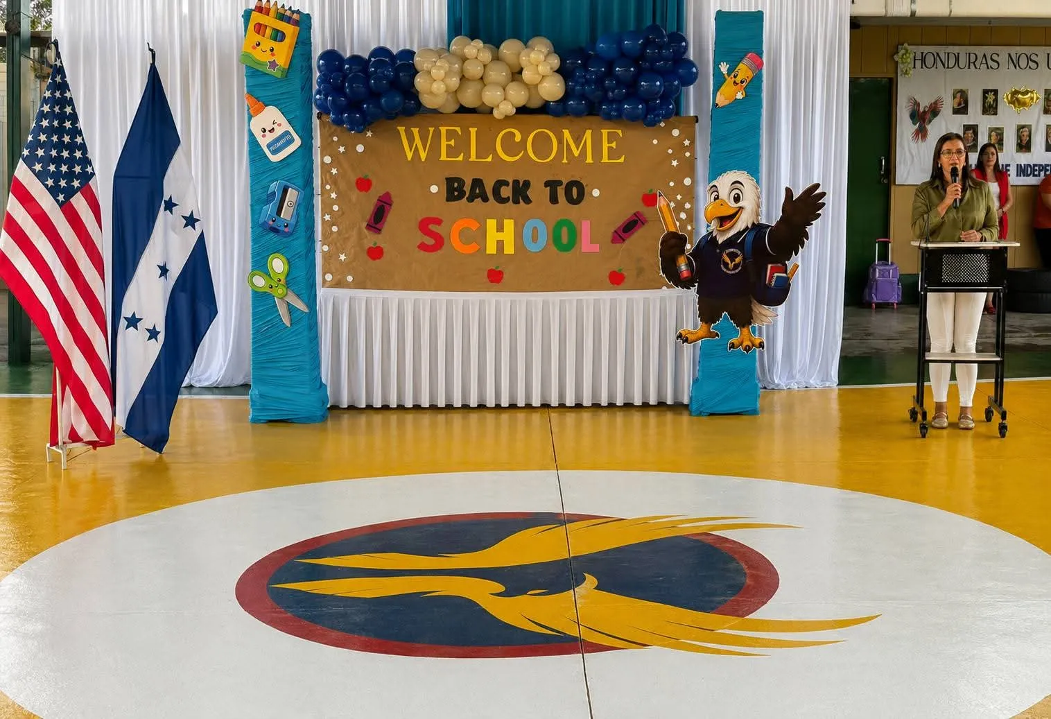 Gimnasio decorado con el mural Welcome Back to School y las banderas de Honduras y Estados Unidos